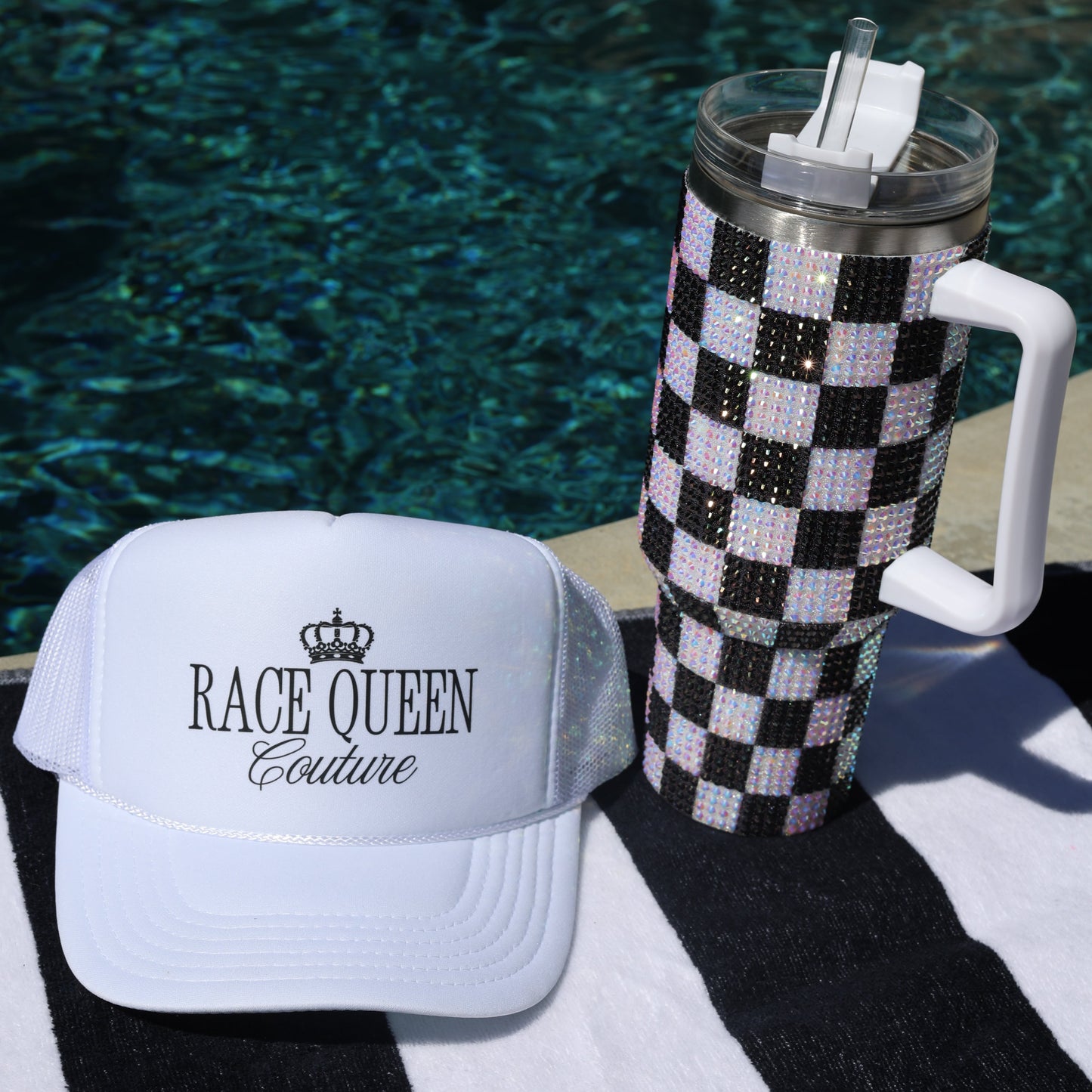 Checkered tumbler with decorative lid on towel with 'Race Queen COuture' branding on white hat