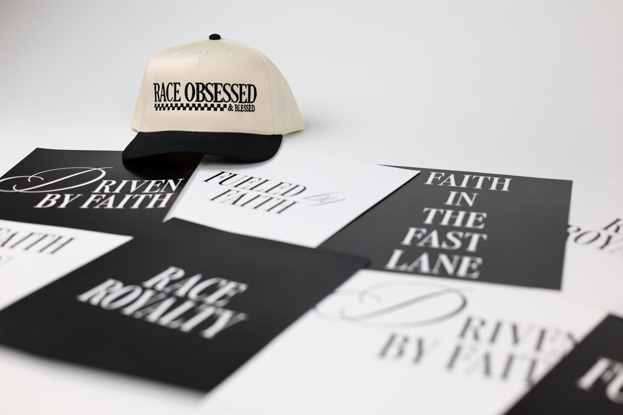 Cap with 'Race Obsessed' text on a white surface with printed cards featuring motivational phrases.