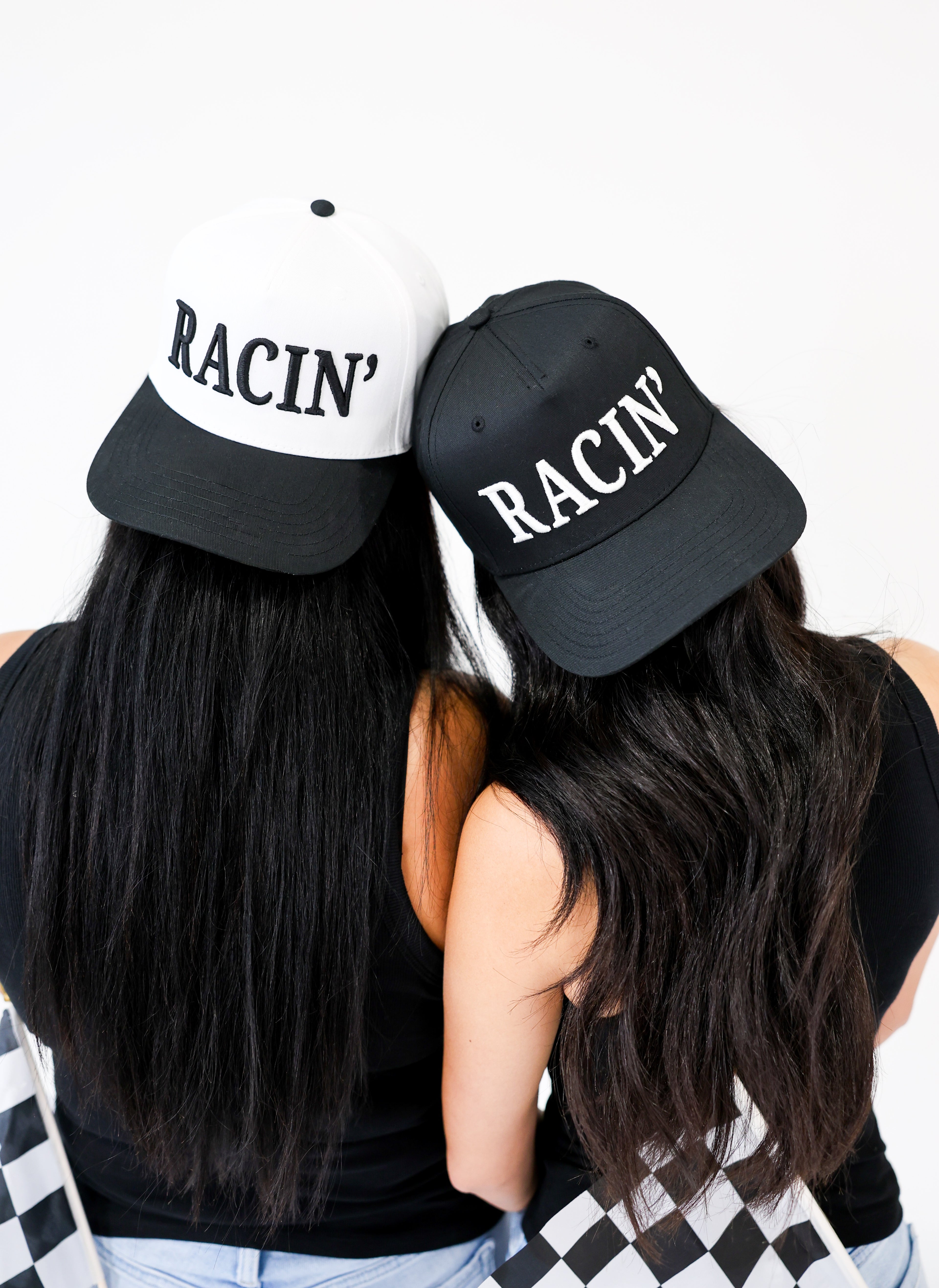 Two people wearing black and white 'Racin' hats on a white background